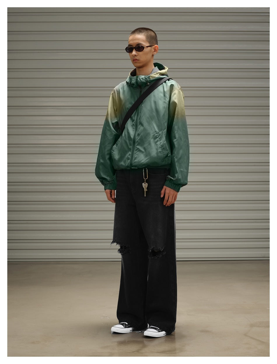 Three-quarter view of a model wearing a green hooded zip jacket and wide black distressed jeans.
