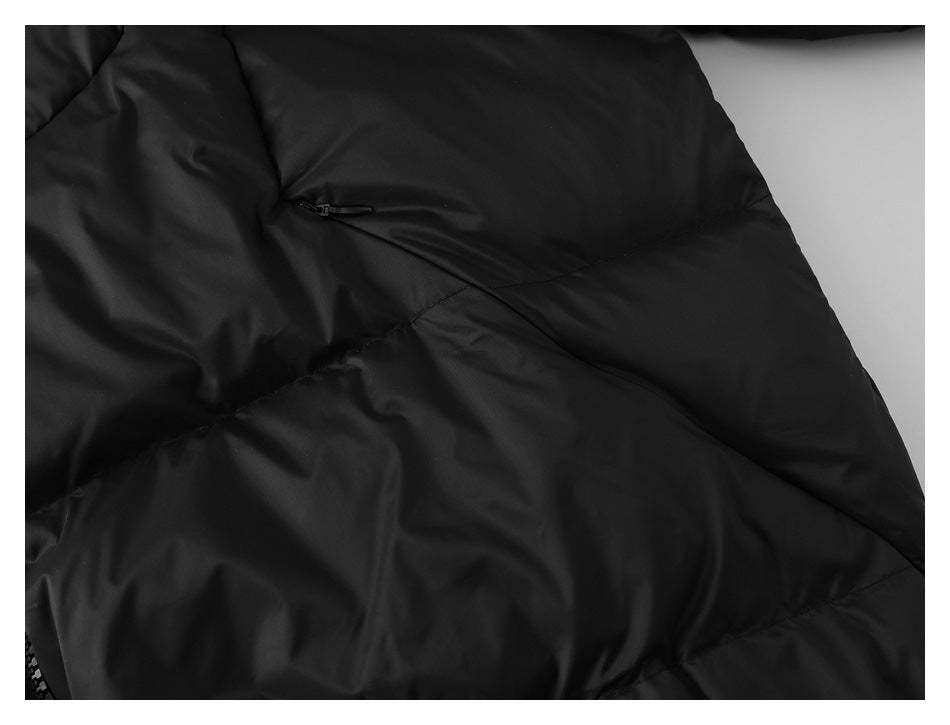 Close-up of a black jacket panel with a small horizontal zip pocket and quilted seams.