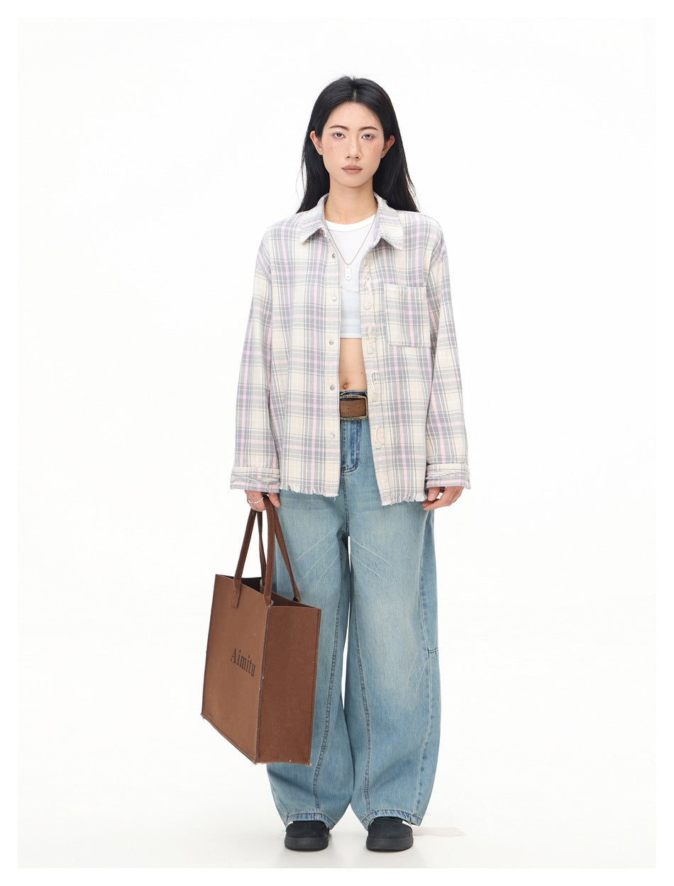 Model wearing pink and gray plaid shirt open over a white crop top with wide-leg jeans and holding a brown tote bag