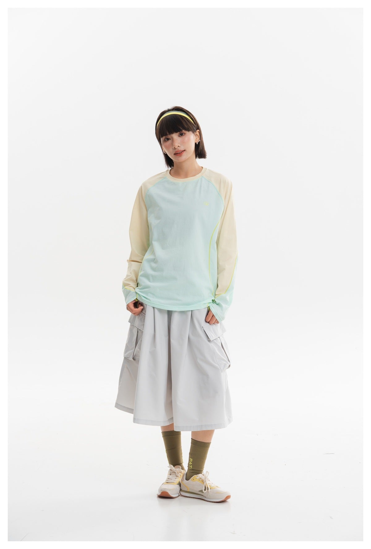 Model wearing a pale aqua raglan long-sleeve top with cream sleeves and a light gray cargo midi skirt, front view.