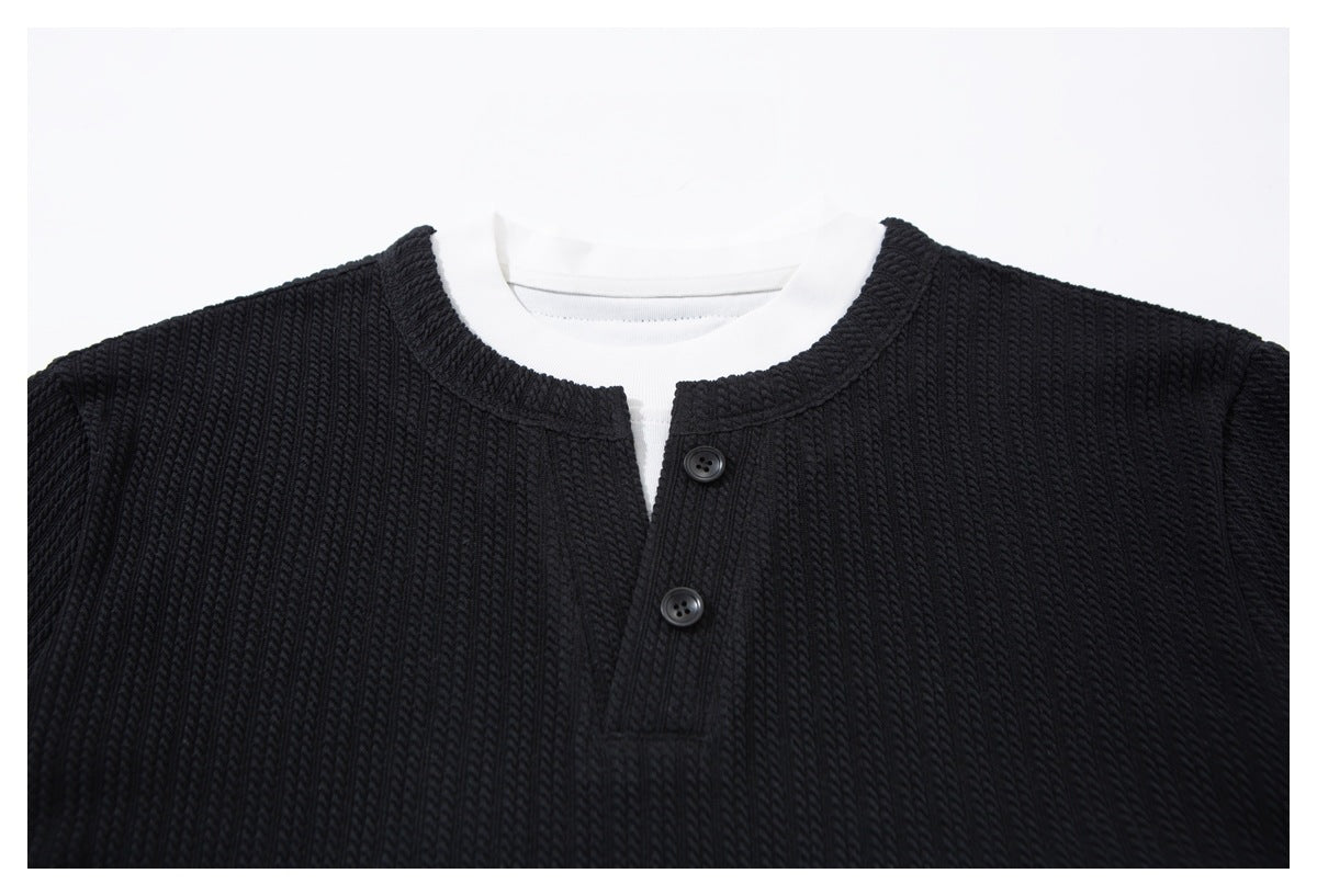 Close-up of the black ribbed henley front, showing its round neckline, two buttons, and white shirt layer.