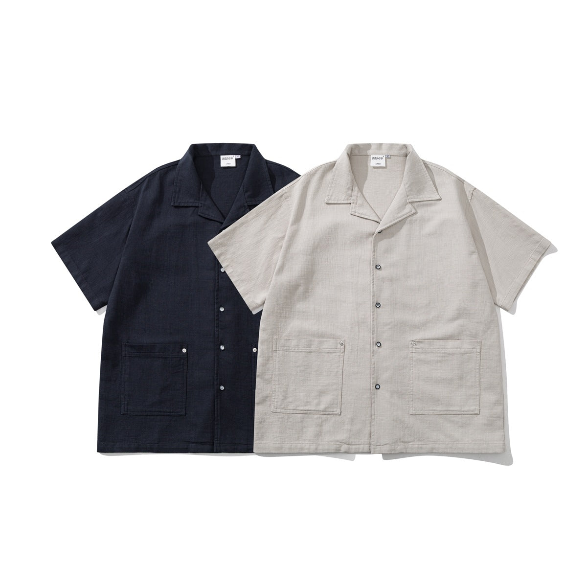 Two short-sleeve shirts shown from the front: one navy and one light beige, each with a notched collar and two lower pockets.