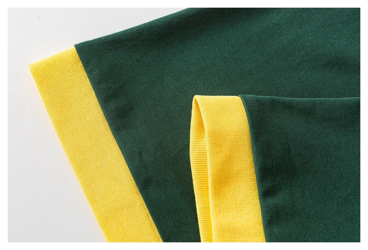 Close-up of a dark green shirt with yellow ribbed trim at the neckline and sleeve edge.
