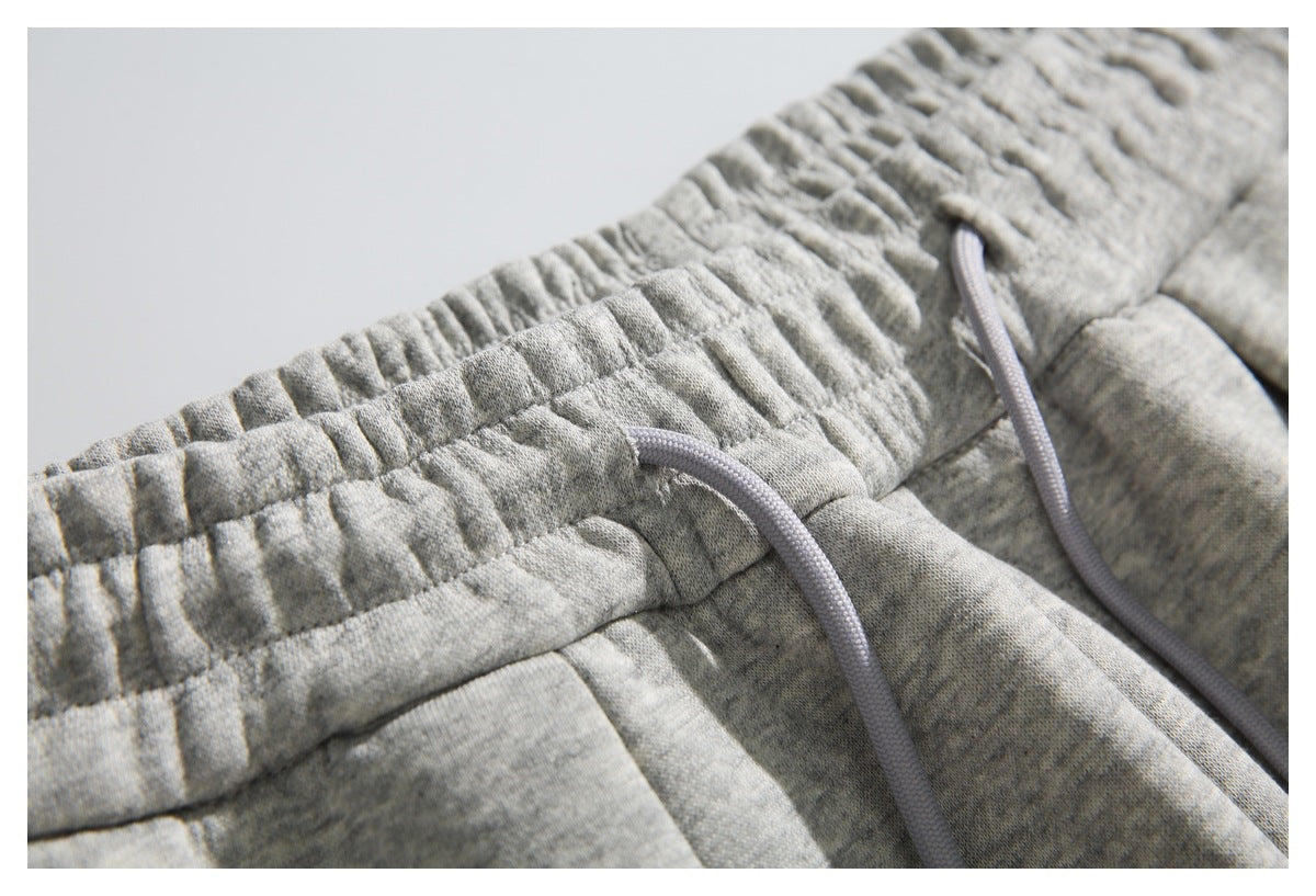 Close-up of the gathered elastic waistband and drawstring eyelets on light gray heather sweatpants.
