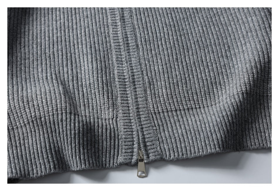 Close-up of a gray ribbed knit garment hem with a metal zipper at the center.