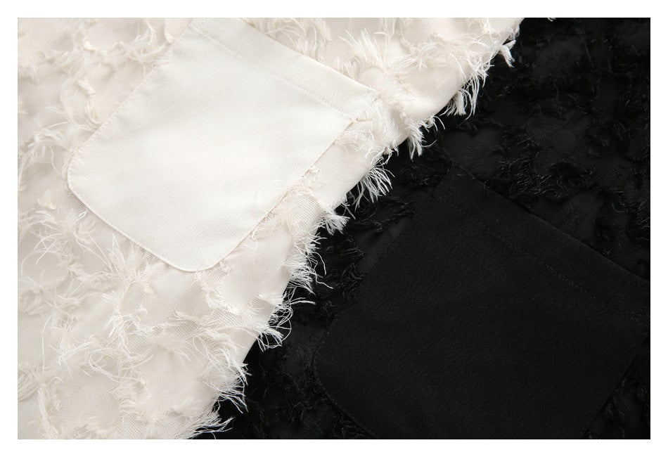 Close-up of white and black garment panels with frayed floral appliqué and matching patch pockets.