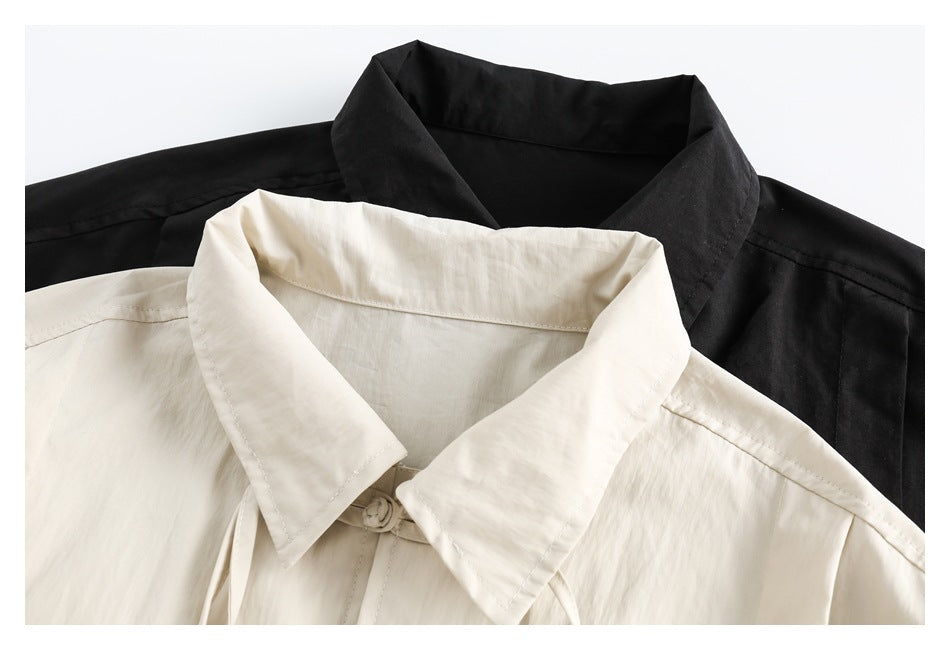 Close-up of overlapping cream and black shirt collars and upper shoulders.