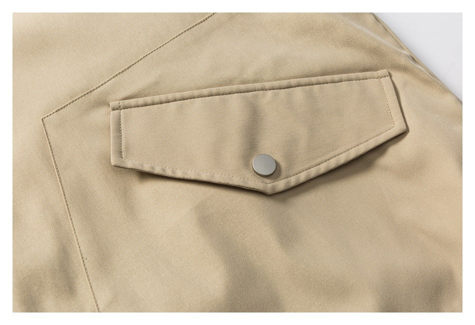 Close-up of a beige jacket's stitched flap pocket with a round metal snap.