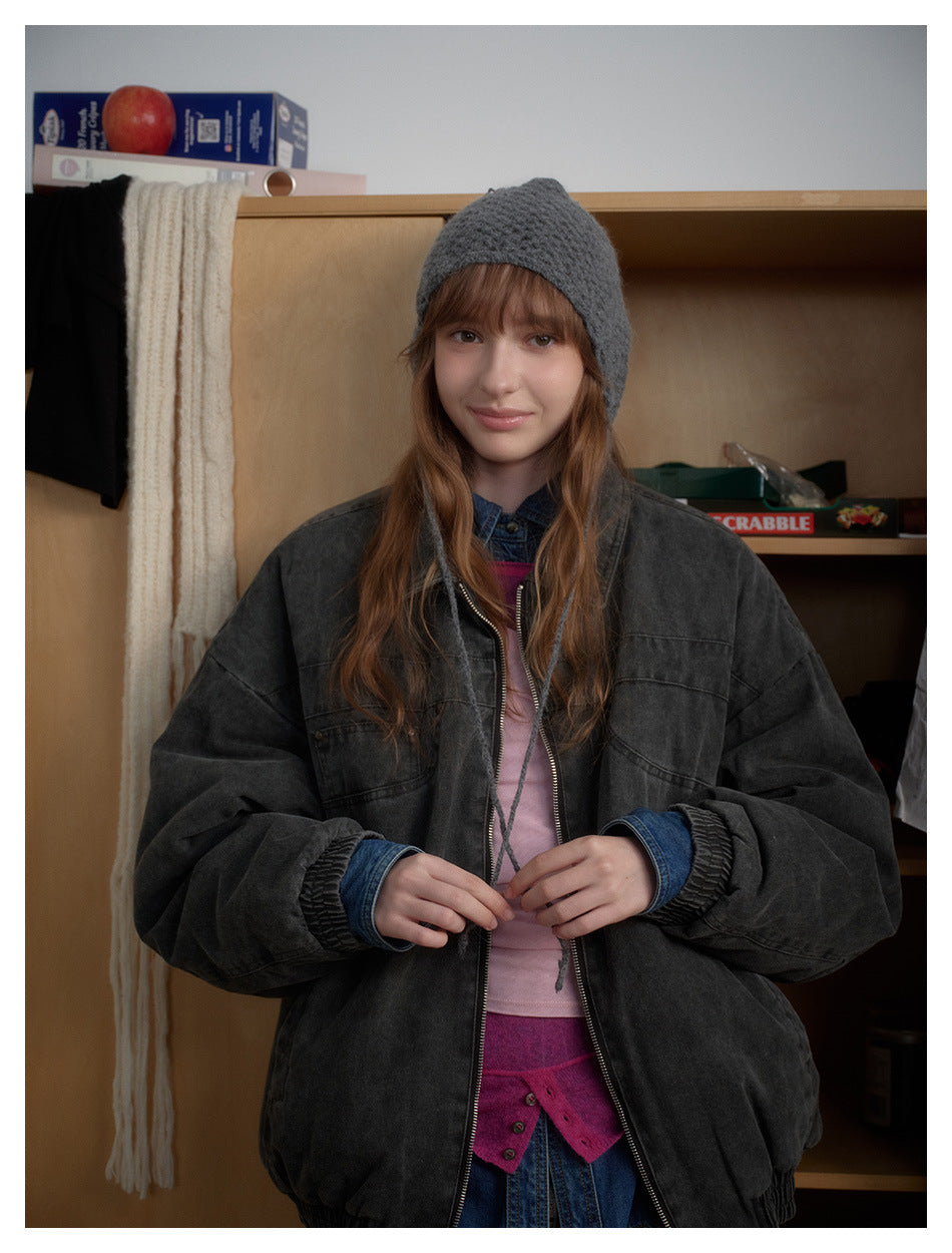 Closer front view of a model wearing an oversized charcoal zip-up jacket over layered pink and denim tops.