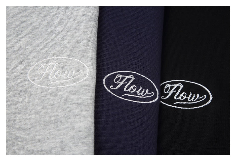 Gray, navy, and black garment colorways with white oval embroidered “Flow” lettering.
