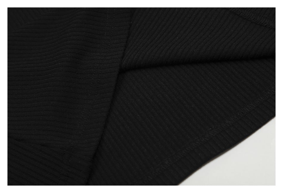 Close-up of folded black ribbed fabric showing seams and edge stitching.