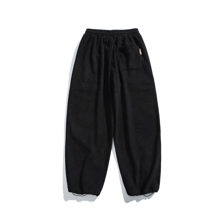 Back view of black jogger pants with an elastic waist, a single patch pocket, and elastic cuffs.