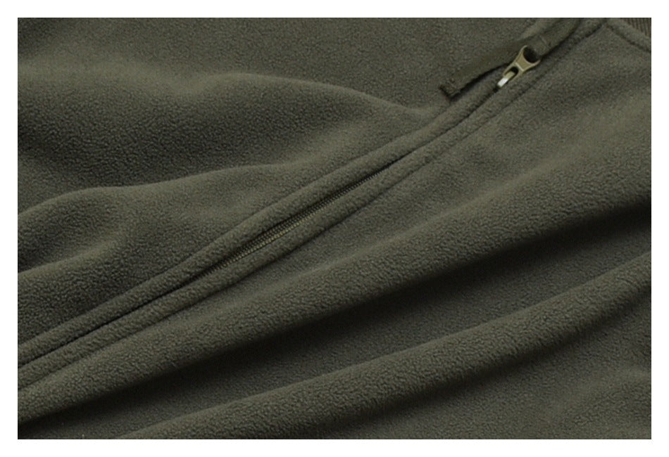 Close-up of dark olive fleece fabric with a diagonal zipper and metal pull.