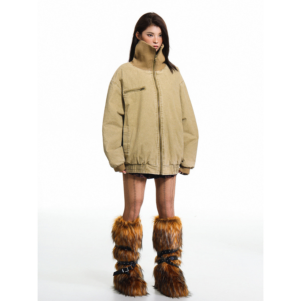 Model wearing an oversized tan zip jacket with a tall collar, chest zipper pocket and gathered hem.
