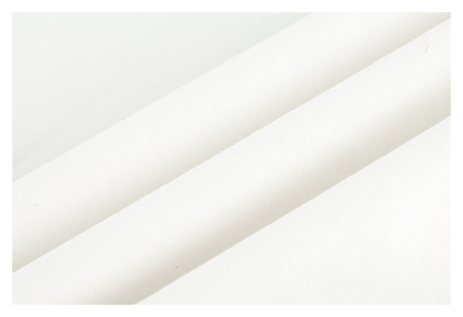 Close-up of white fabric folded into diagonal ridges, showing its fine surface texture.