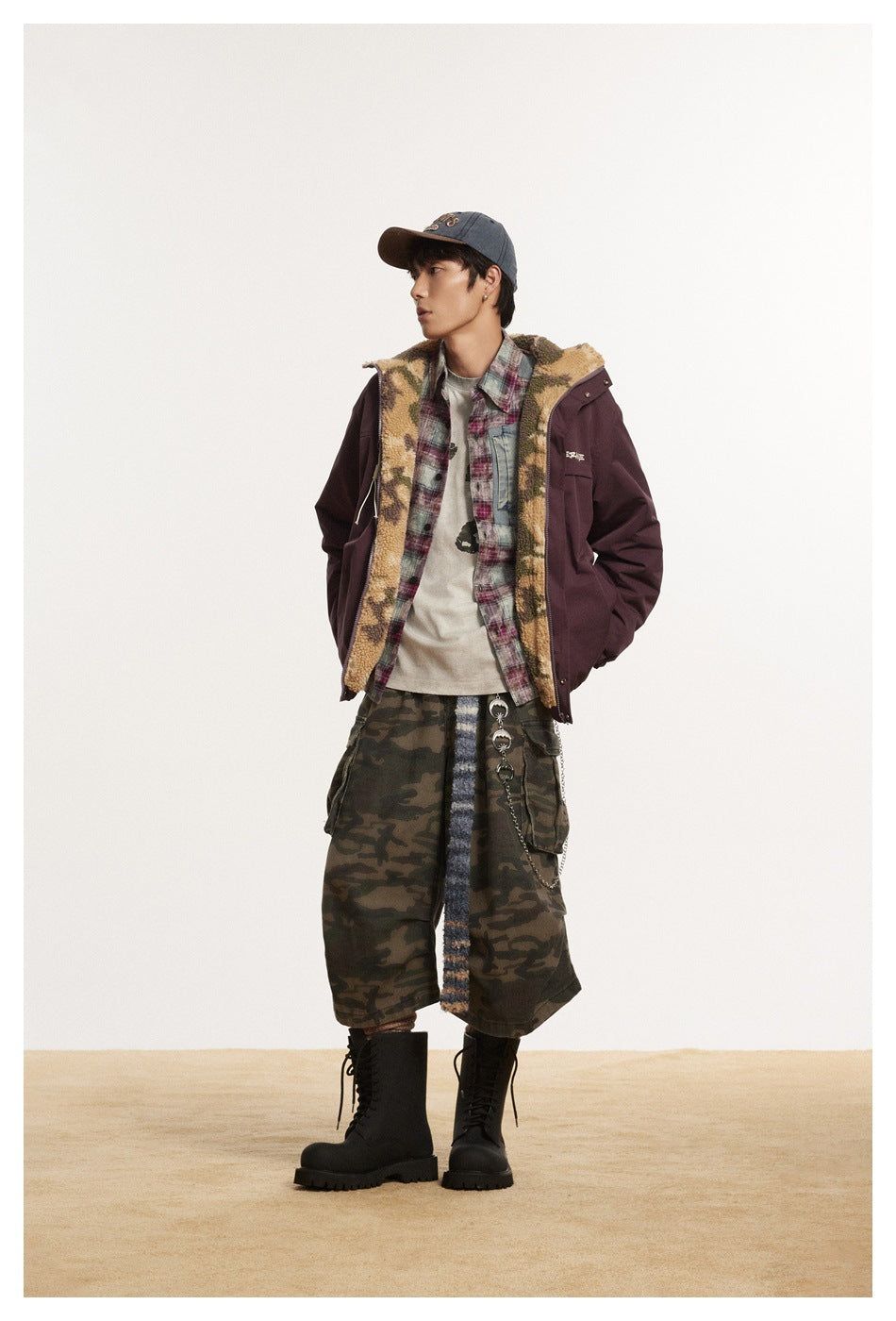 Model wearing the burgundy jacket open over a plaid shirt, revealing the camouflage fleece-like lining, with camo pants