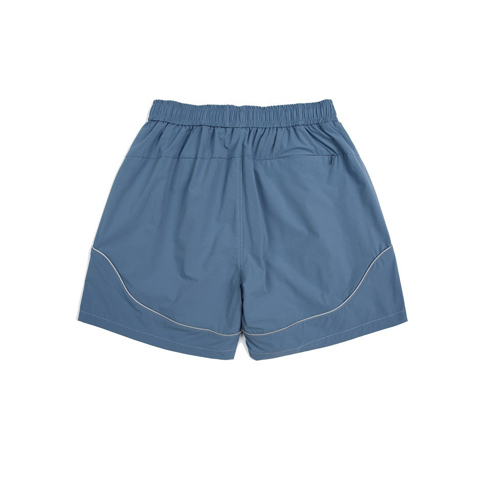 Blue athletic shorts, back view, with an elastic waistband, small zip pocket, and curved light piping.
