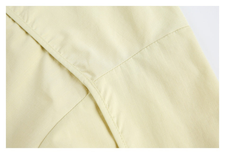 Close-up showing a curved stitched seam on pale yellow garment fabric.