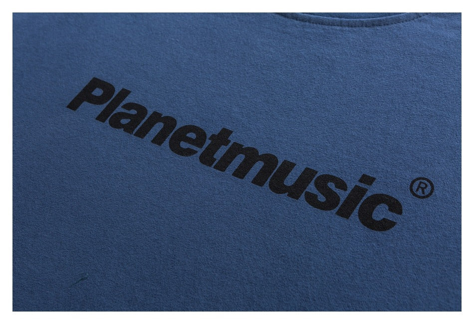 Close-up of a blue T-shirt with a large black Planetmusic logo printed across the chest.