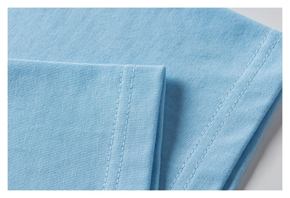 Close-up of light blue knit garment fabric with a folded edge and parallel stitching.