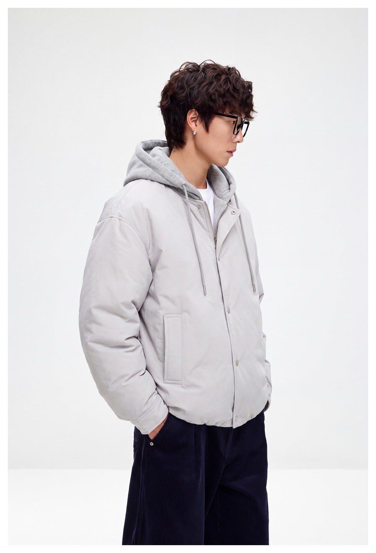 Model in a light gray hooded jacket with snap closure and front pockets, shown from a side angle.