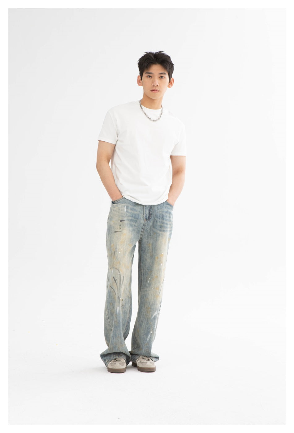 Model wearing a plain white crew-neck T-shirt and loose, distressed light-wash jeans, hands in pockets.