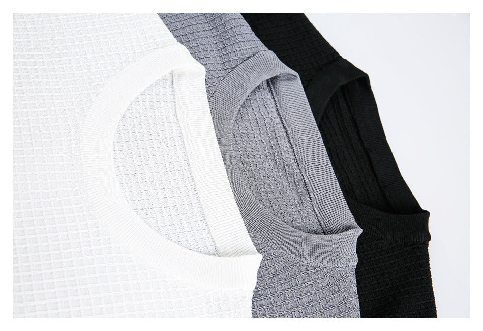 Close-up of white, gray, and black knit shirts showing their ribbed crew necklines and textured fabric.