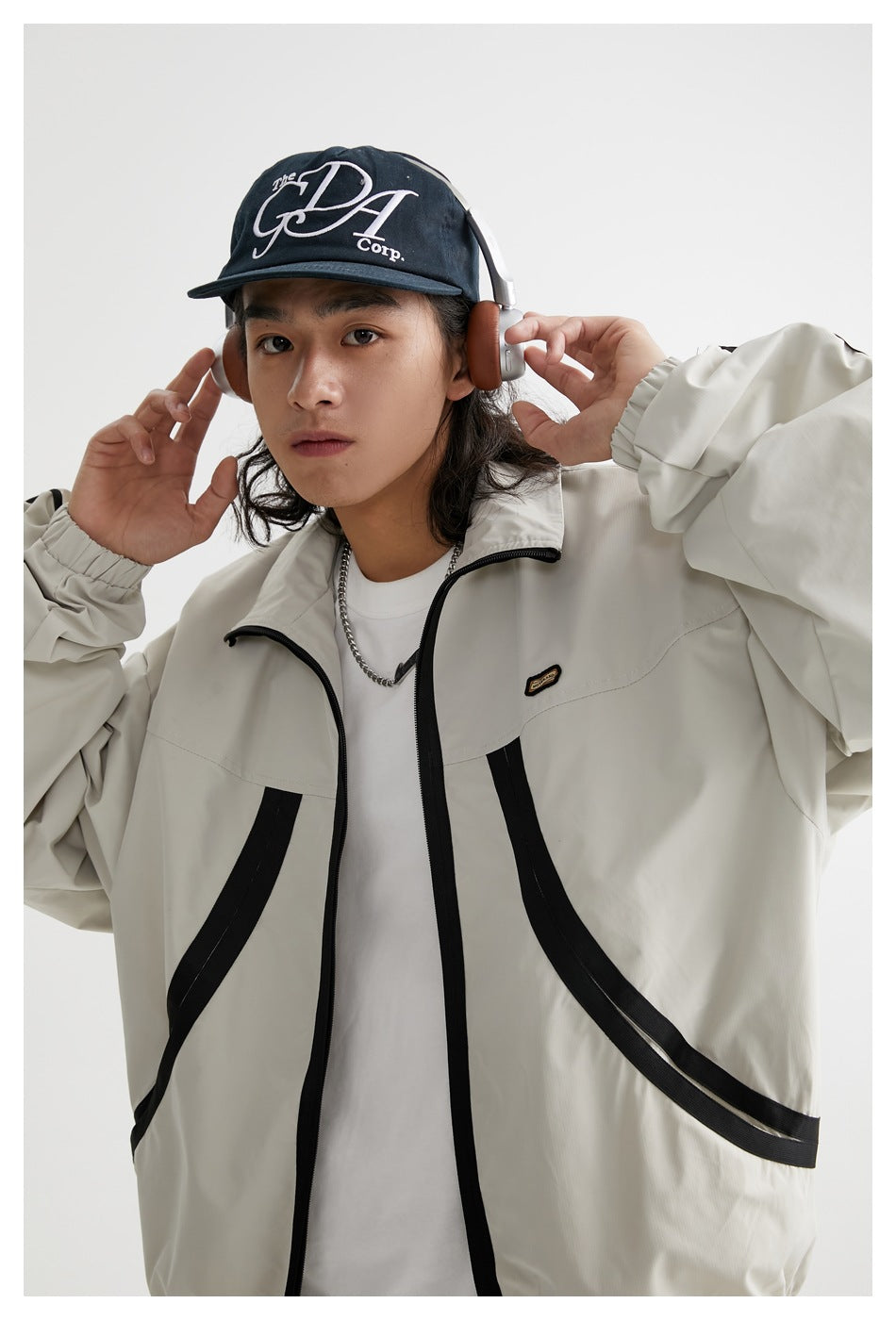 Close view of a model wearing a light gray jacket with black front trim and a small chest patch.