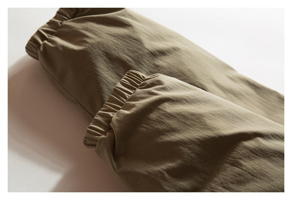 Close-up of gathered elastic cuffs on olive-khaki garment legs.