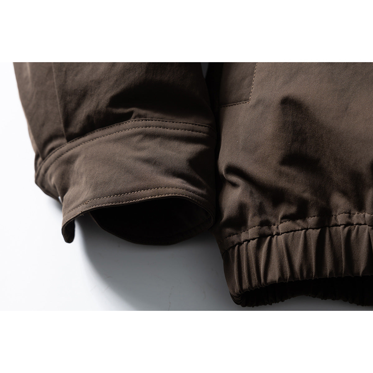 Close-up of a dark brown jacket sleeve cuff and gathered elastic hem.