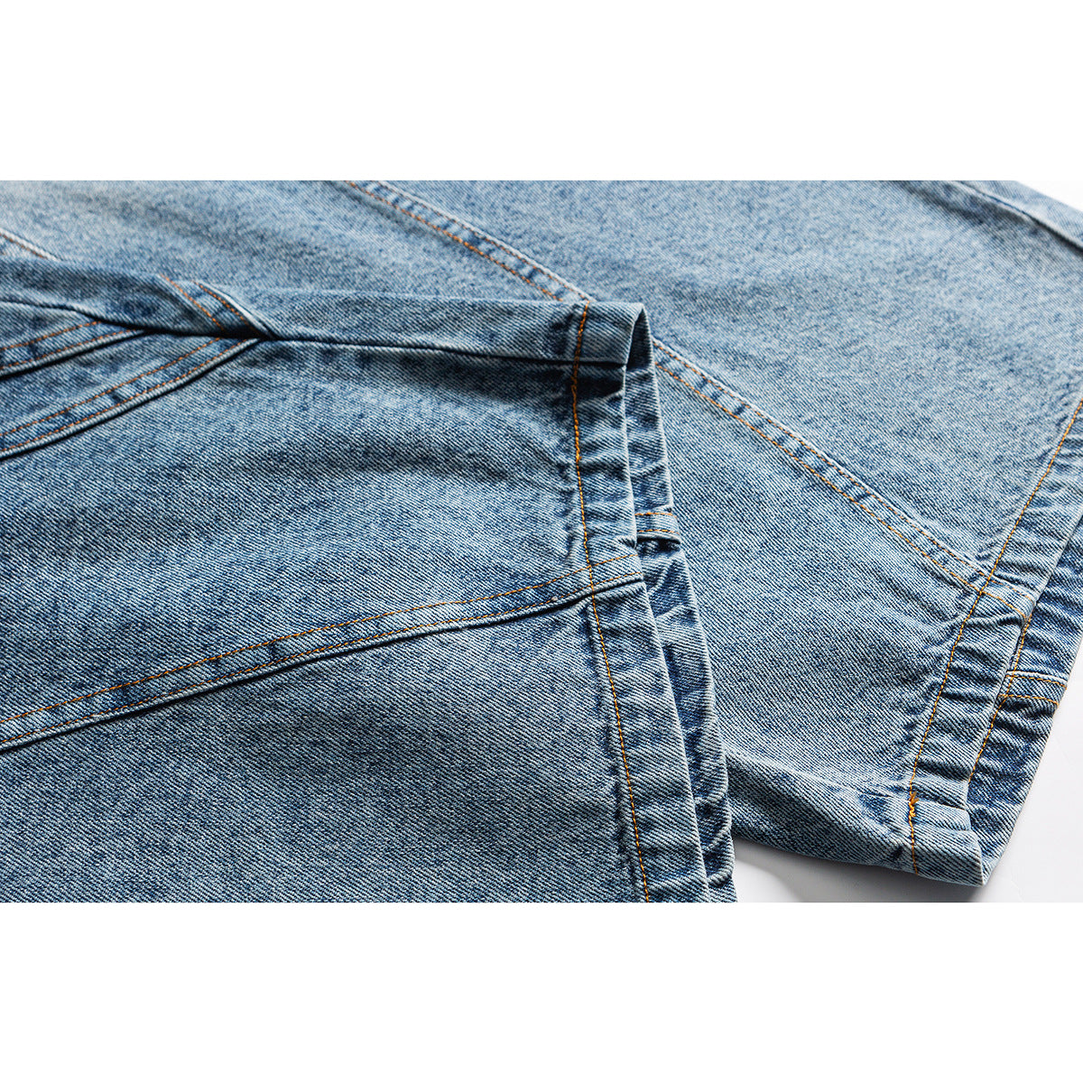 Close-up of light blue denim leg panels, seams, and folded hems.