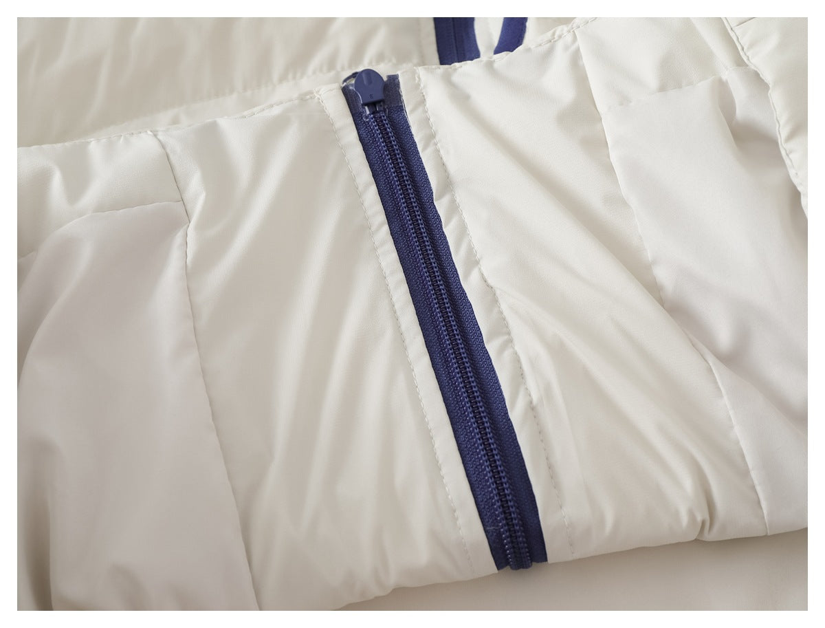 Close-up of the dark blue front zipper on a white quilted jacket.