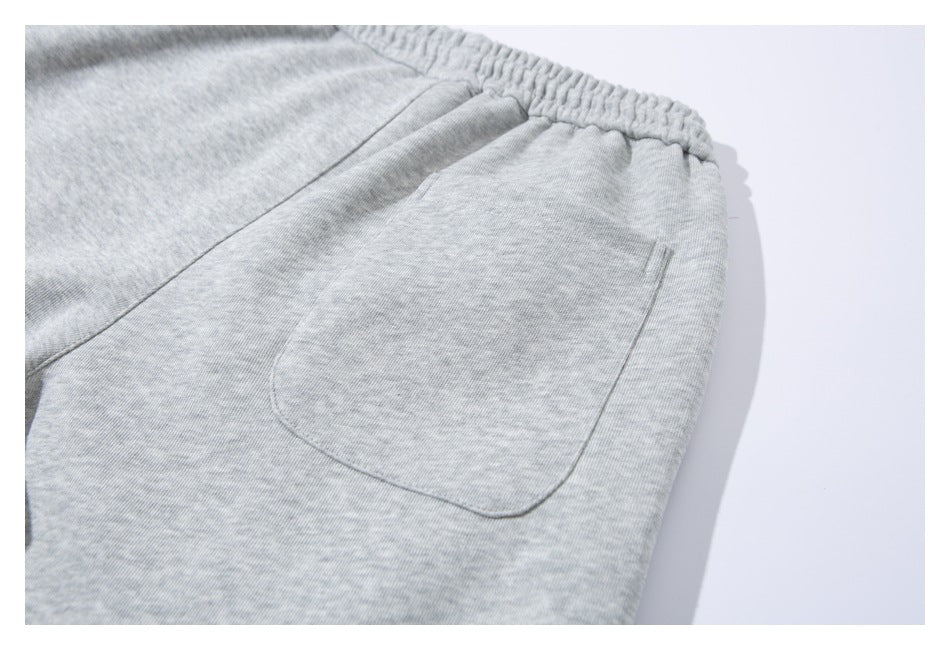 Close-up of a light gray pair of sweatpants showing the elastic waistband and a large patch pocket.