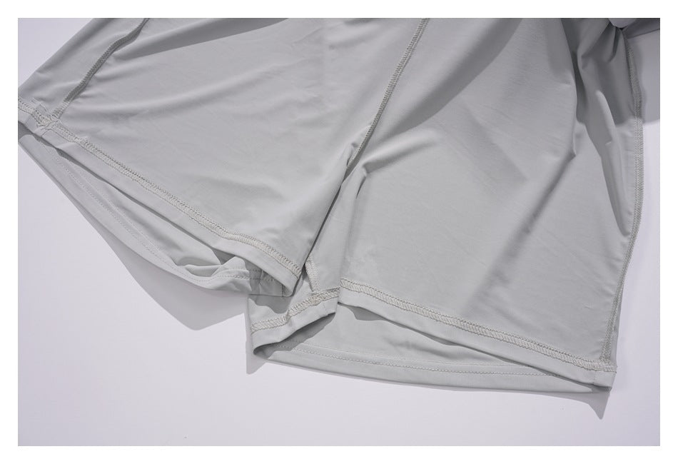 Close-up of light gray garment panels showing interior seams, overlock stitching, and a folded hem.