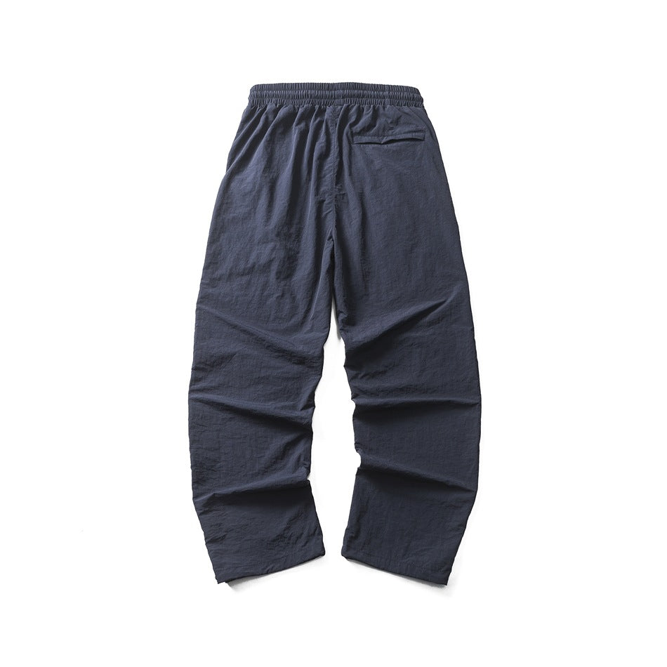 Back view of loose navy pants laid flat, with an elastic waistband and a single rear pocket.