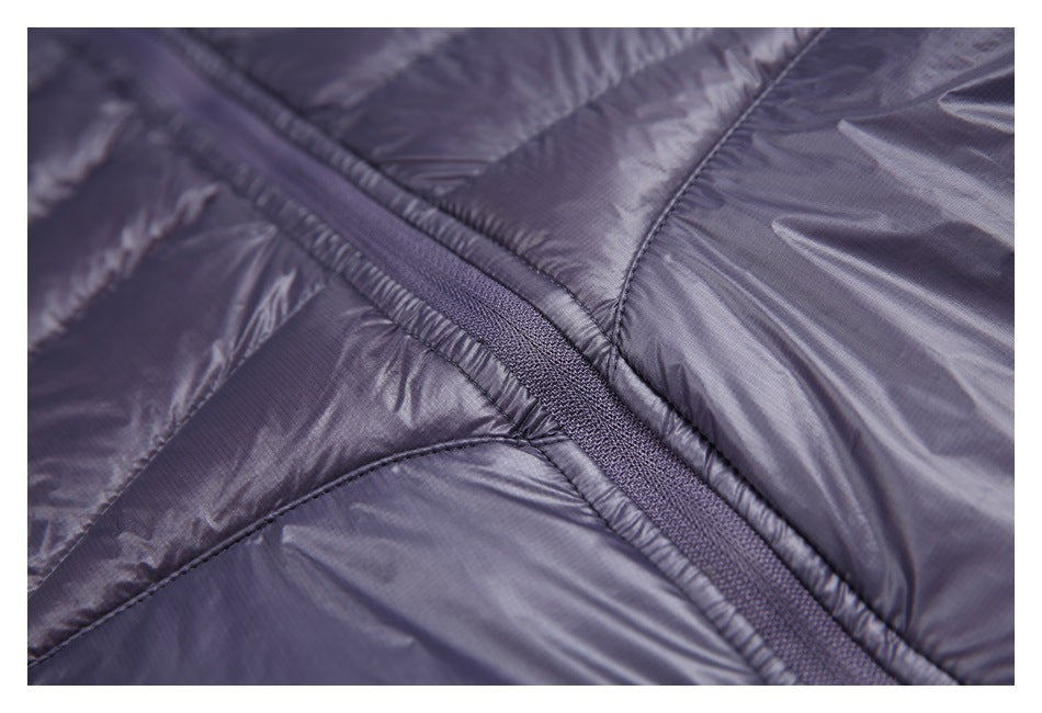 Close-up of a dark purple jacket zipper crossing between stitched padded panels.
