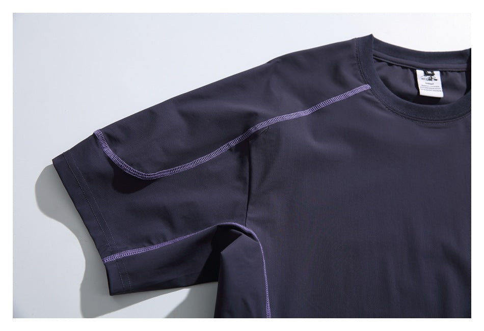 Close-up of a dark navy T-shirt sleeve and upper front, showing contrasting purple overlock seams.