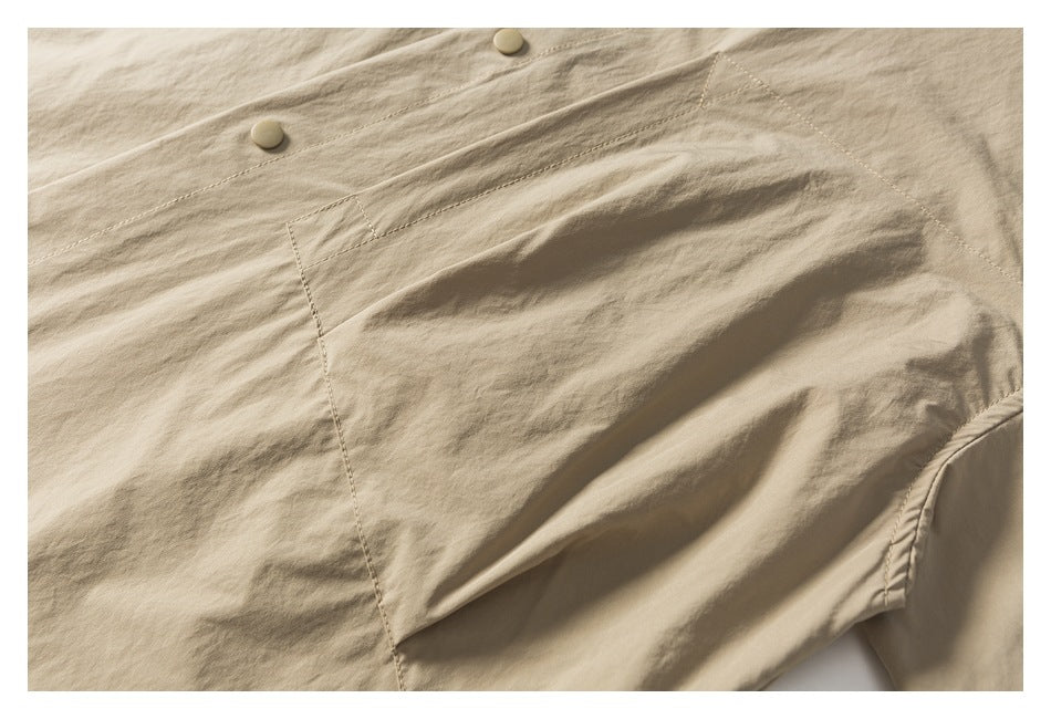 Close-up of the beige shirt's chest pocket, button placket, and stitching.