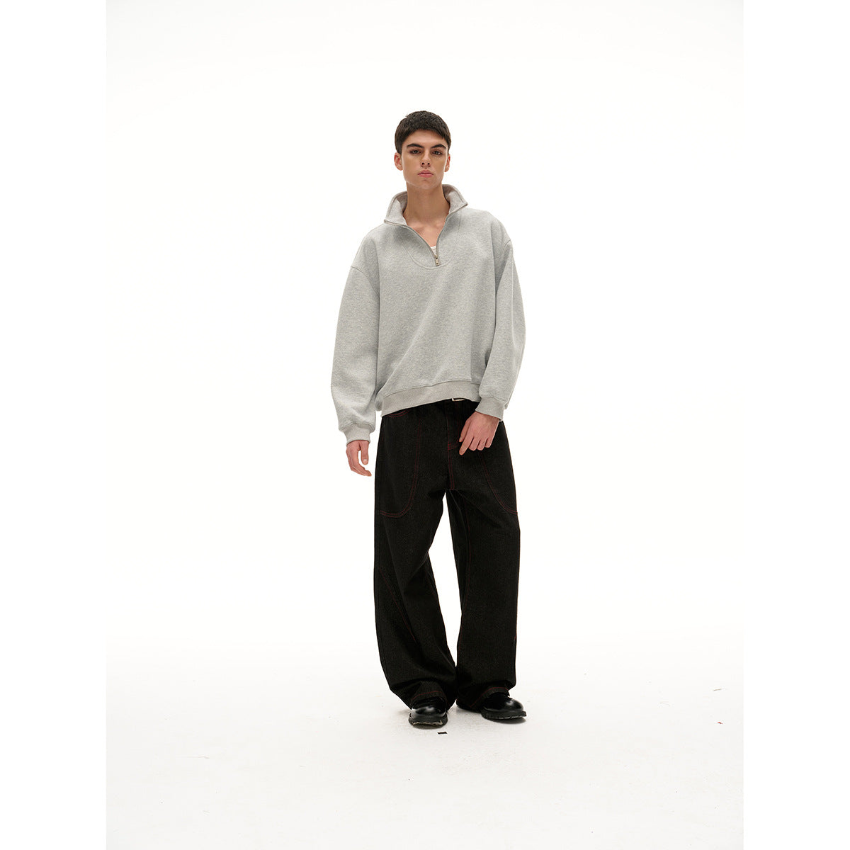 Front view of a model wearing a light gray quarter-zip pullover, black wide-leg pants, and black shoes.