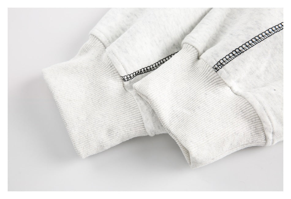 Close-up of an off-white sweatshirt sleeve cuff with ribbed trim and black contrast stitching.