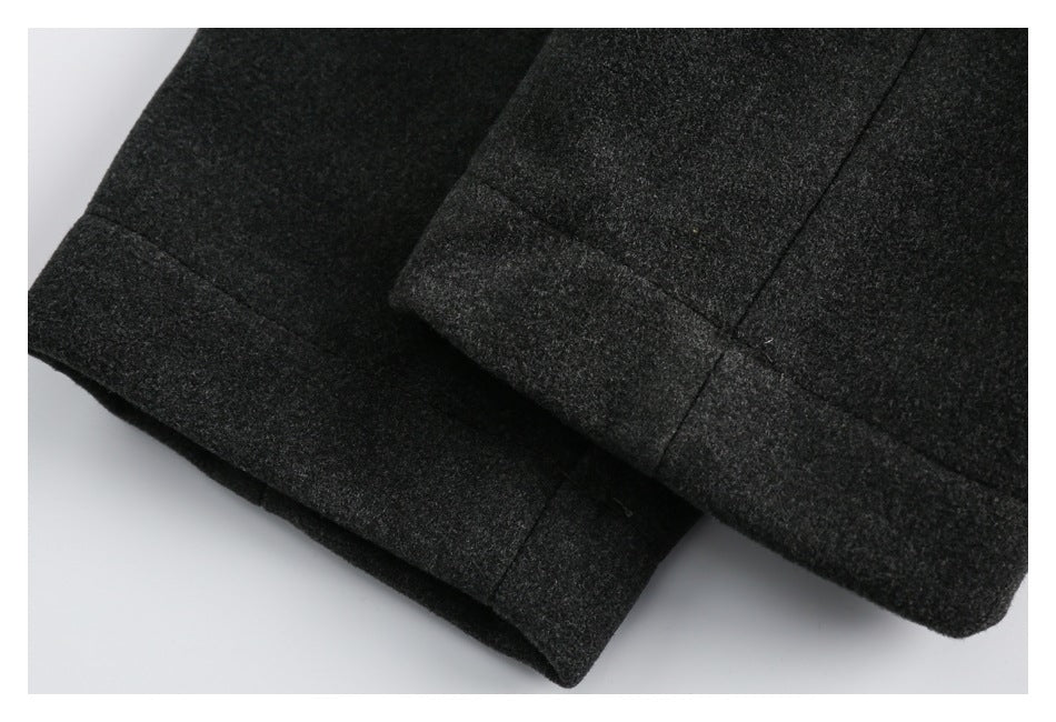 Close-up of the charcoal coat's folded hem edges and visible stitching.