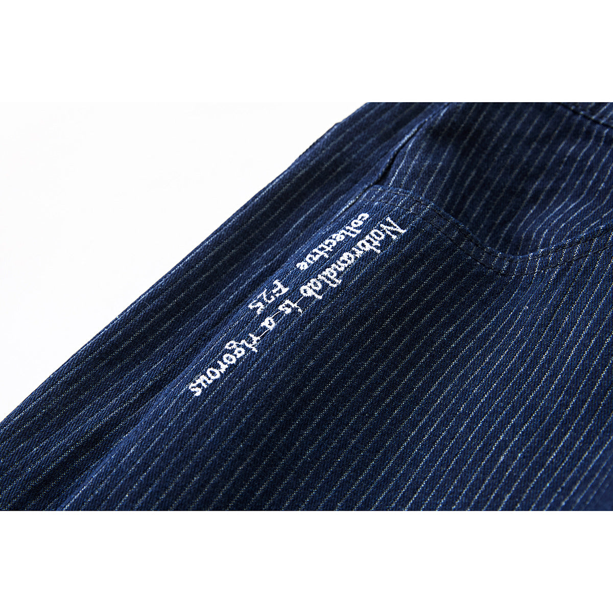 Close-up of navy pinstriped shorts with small white lettering stitched beside a pocket.