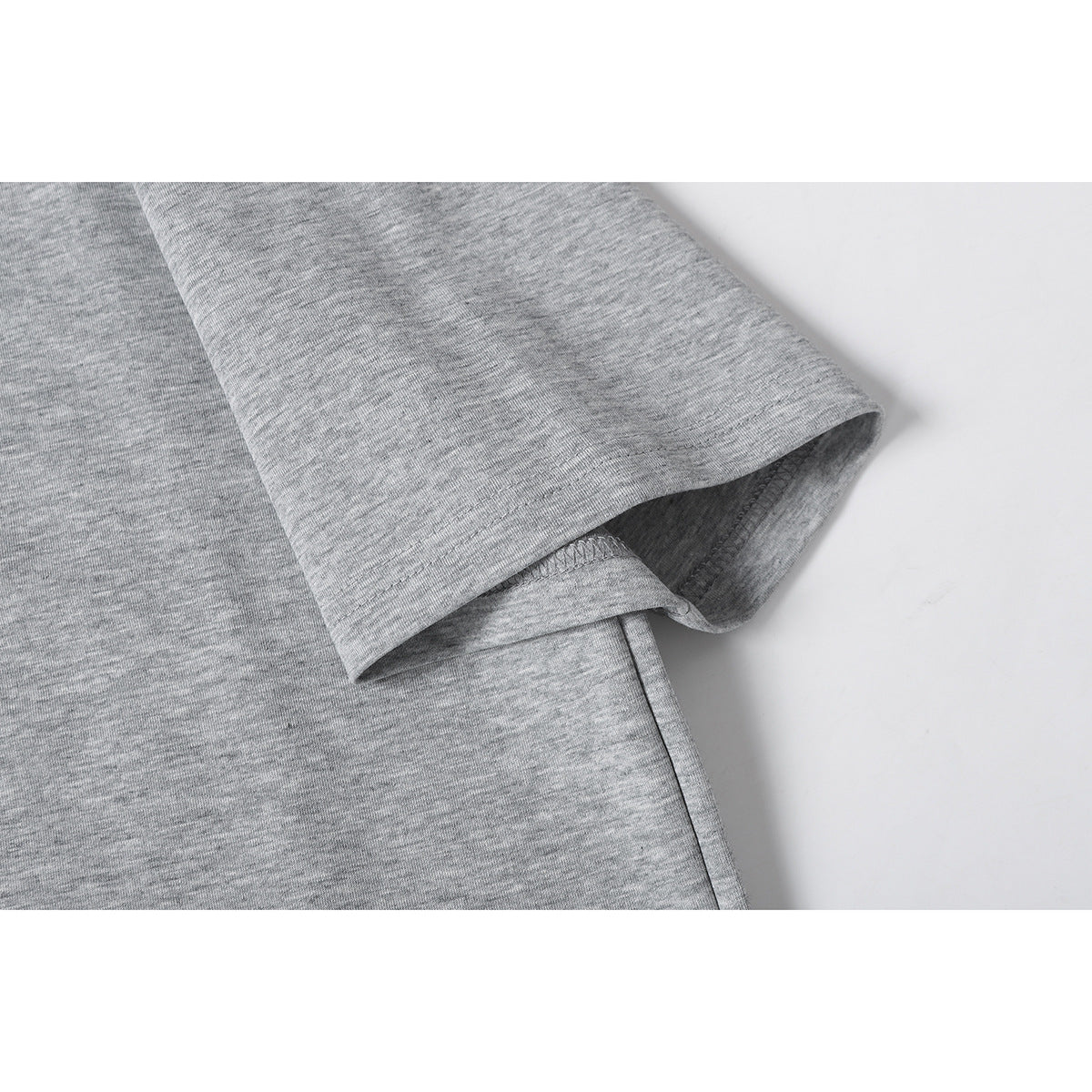 Close-up of the short sleeve and stitched hem on a heather gray T-shirt.