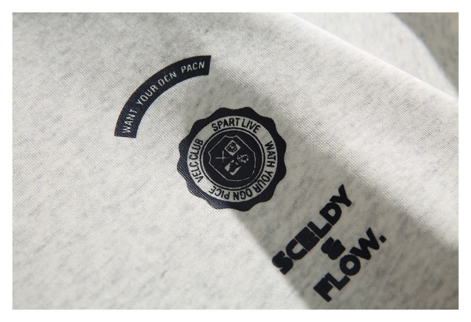 Close-up of black text and emblem graphics printed on the off-white heathered sweatshirt.