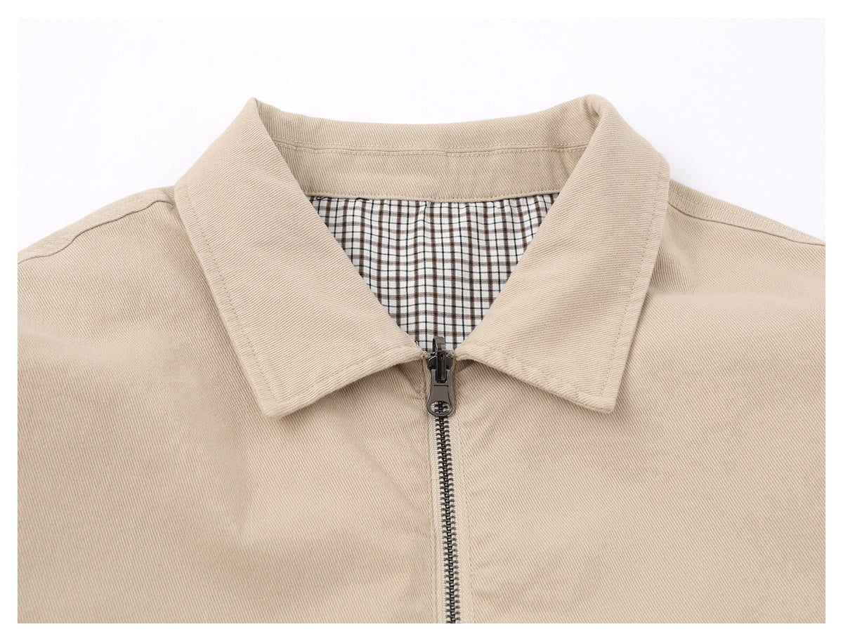 Close-up of a beige jacket's pointed collar, front zipper, and brown-and-white checked lining.