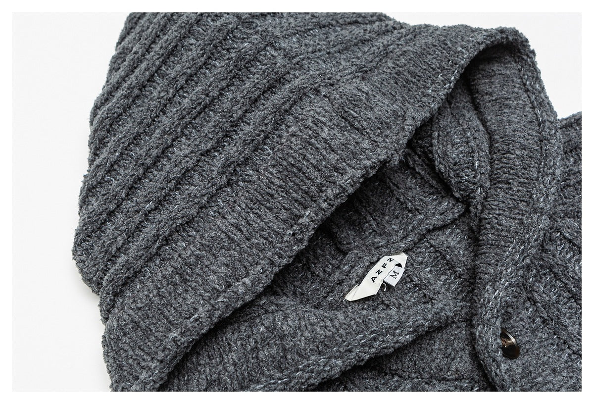 Close-up of the dark charcoal knit garment's folded collar, sewn neck labels, and a dark button.