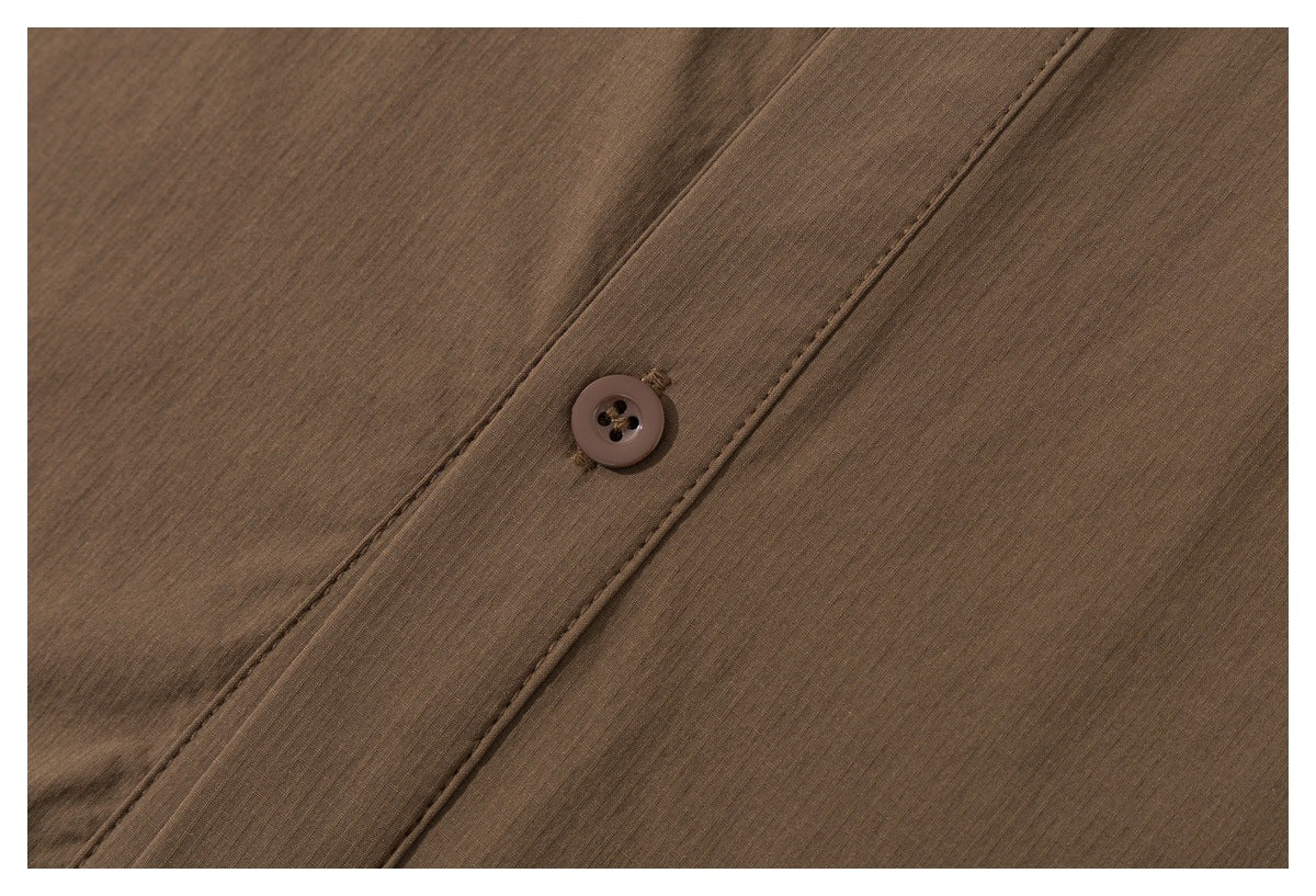 Close-up of a brown button and stitched placket on the brown shirt.