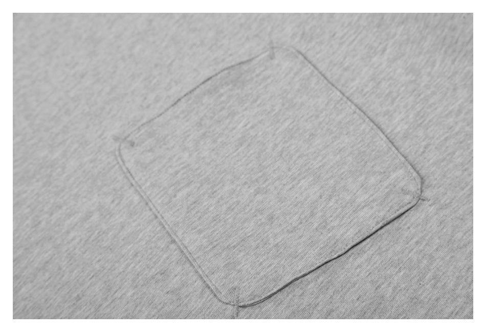 Close-up of a stitched square chest pocket on heather gray T-shirt fabric.