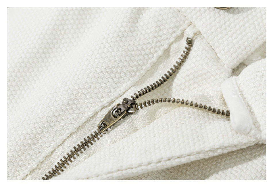Close-up of a metal zipper on an ivory textured garment.