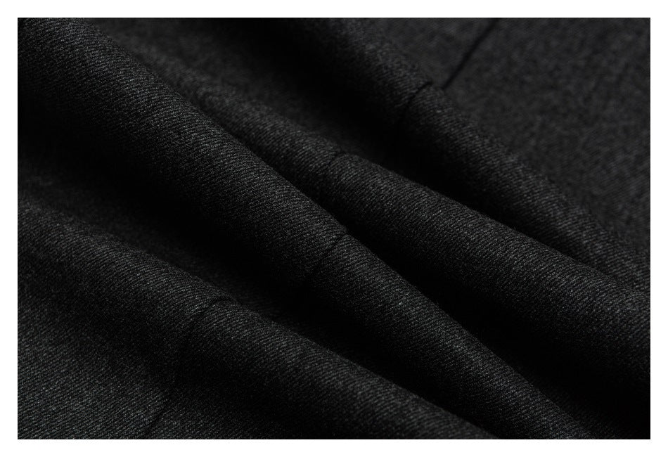 Close-up of charcoal trouser fabric arranged in soft folds.